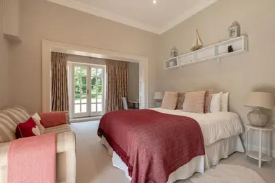 a bedroom with a large bed and a chair at 5 Bed in Orford oc-pav in Orford