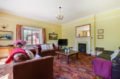 a living room with a woman laying on a couch at 13 Bed in Tattingstone oc-tat26 in Tattingstone