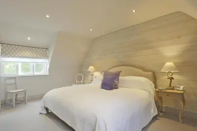 a bedroom with a large white bed with a wooden wall at 2 Bed in Thorpeness oc-vels in Thorpeness
