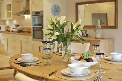 a wooden table with a vase of flowers on it at 2 Bed in Thorpeness oc-vels in Thorpeness