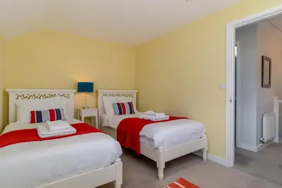 a bedroom with two beds with red and white sheets at 3 Bed in Knodishall oc-wbco in Aldringham