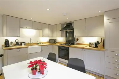 a kitchen with white cabinets and a table with flowers on it at 2 Bed in Aldeburgh oc-tsc in Aldeburgh