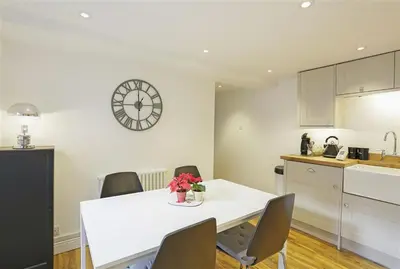 a kitchen with a white table and a clock on the wall at 2 Bed in Aldeburgh oc-tsc in Aldeburgh