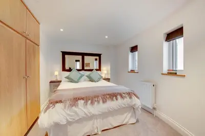 a bedroom with a bed with a mirror and windows at 2 Bed in Woodbridge oc-zep in Woodbridge