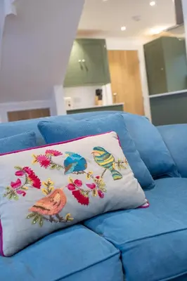 a blue couch with a pillow with birds on it at 2 Bed in Woodbridge oc-zep in Woodbridge