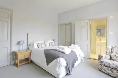 a white bedroom with a bed and a chair at 2 Bed in Orford oc-sfwco in Orford