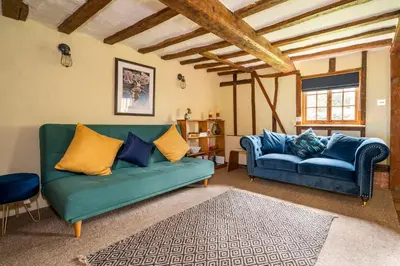 a living room with two blue couches and a rug at Buttercup Cottage, Hartest in Hartest