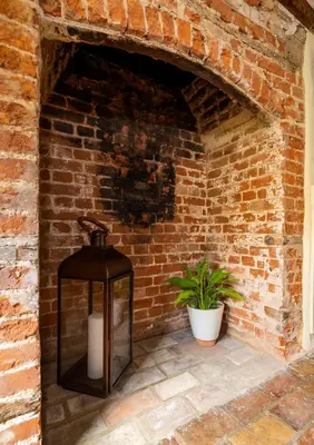 a lantern against a brick wall with a plant at Buttercup Cottage, Hartest in Hartest