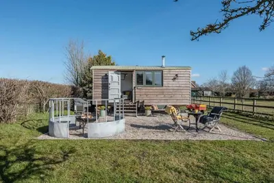 a tiny house with a patio and a table and chairs at Lily Pad, Friston in Saxmundham