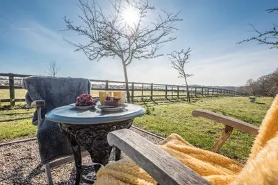 a table and a chair in a field with a fence at Lily Pad, Friston in Saxmundham