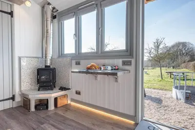 a living room with a stove in a tiny house at Lily Pad, Friston in Saxmundham