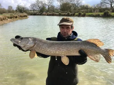 a man holding a large fish in the water at ROSE CHALET in Framlingham