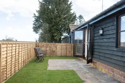 a backyard with a wooden fence and a chair at ROSE CHALET in Framlingham