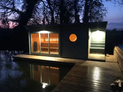 a tiny house sitting on top of a body of water at The Woodpecker shepherd hut in Elmswell