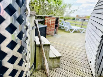 a wooden deck with a bench and a fence at Armadilla 1 at Lee Wick Farm Cottages & Glamping in Clacton-on-Sea