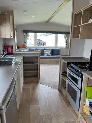 a kitchen with a stove and a couch in the background at Arizona - Pura Vida Holidays Caravan in Clacton-on-Sea