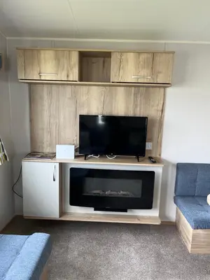 a living room with a entertainment center with a flat screen tv at Arizona - Pura Vida Holidays Caravan in Clacton-on-Sea