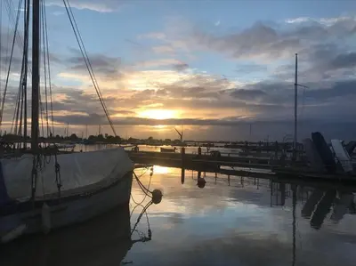 a boat docked at a marina with the sun setting at Harbour Walk in Brightlingsea