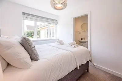 a white bedroom with a large bed and a window at Springfield, Westleton in Westleton