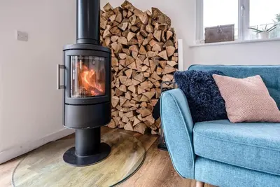 a wood burning stove in a living room with a blue couch at Springfield, Westleton in Westleton