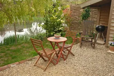 a table and two chairs sitting next to a lake at Mustard Pot Cottage in Eye