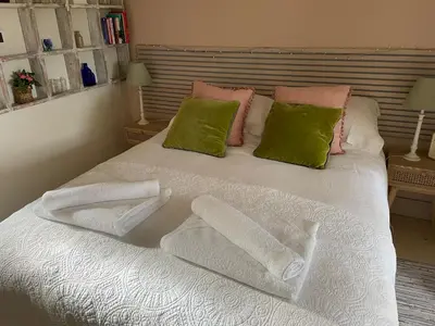 a bed with white sheets and green pillows at Mustard Pot Cottage in Eye