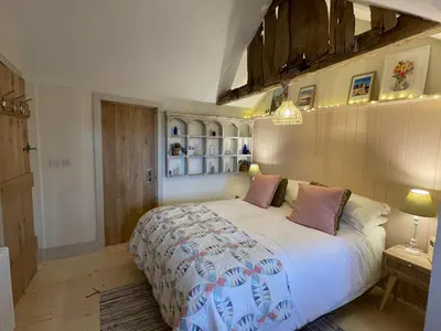 a bedroom with a large white bed with purple pillows at Mustard Pot Cottage in Eye