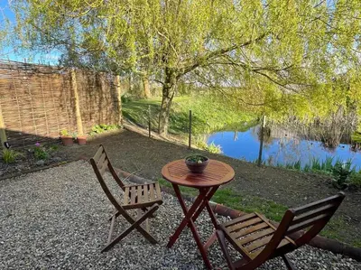 a table and two chairs sitting next to a lake at Mustard Pot Cottage in Eye