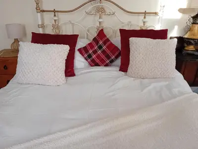 a white bed with red and white pillows on it at Owls Roost in Stowmarket