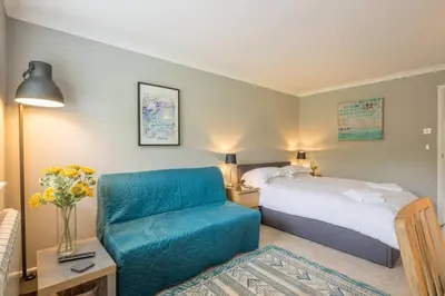 a hotel room with a bed and a blue chair at Addenbrookes Flat 2 mins walk free Private Parking in Cambridge