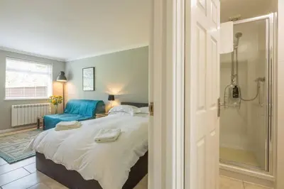 a bedroom with a large bed and a blue chair at Addenbrookes Flat 2 mins walk free Private Parking in Cambridge