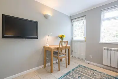 a room with a desk and a television on a wall at Addenbrookes Flat 2 mins walk free Private Parking in Cambridge
