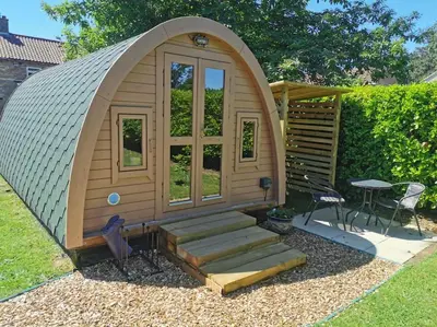 a small wooden iguana house with stairs and a table at The Chestnuts Pod with private garden. in Eccles