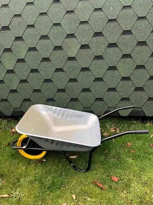 a wheelbarrow sitting on the grass next to a wall at The Chestnuts Pod with private garden. in Eccles