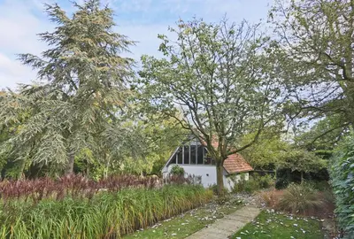 a garden with a white building in the background at 6 Bed in Lavenham oc-stofa in Lavenham