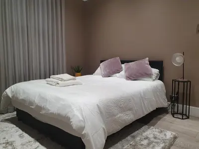 a bedroom with a large bed with white sheets and purple pillows at The Westcliff Room in Southend-on-Sea
