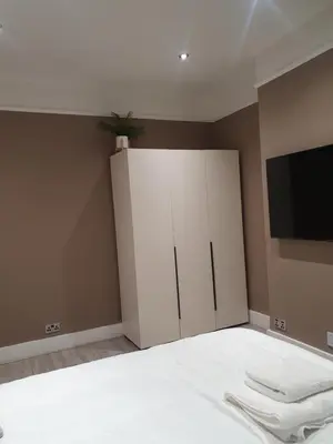 a bedroom with a white cabinet and a tv at The Westcliff Room in Southend-on-Sea