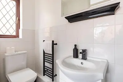 a white bathroom with a sink and a toilet at House on cul de sac in Lakenheath