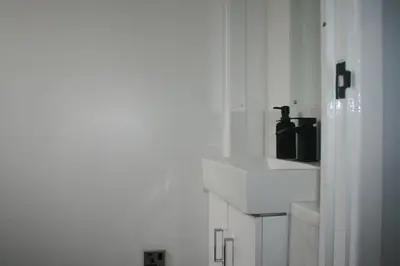 a white bathroom with a sink and a mirror at House on cul de sac in Lakenheath