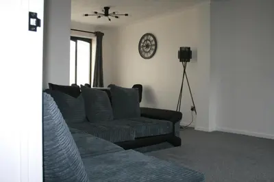 a living room with a couch and a clock on the wall at House on cul de sac in Lakenheath