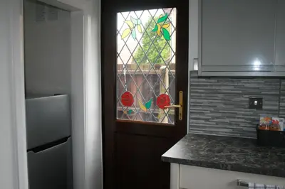 a kitchen with a door with a stained glass window at House on cul de sac in Lakenheath