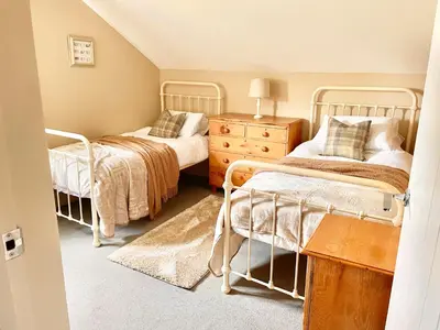 a bedroom with two beds and a wooden dresser at The Hayloft in Gestingthorpe