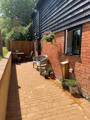 a patio with a bench next to a brick building at The Hayloft in Gestingthorpe