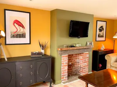 a living room with a fireplace and a flat screen tv at The Hayloft in Gestingthorpe