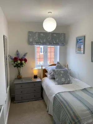 a bedroom with a bed and a window with a vase of flowers at Comfortable new home in Isleham in Ely