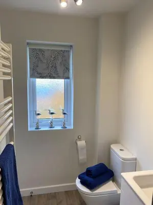 a bathroom with a toilet and a window with a blue towel at Comfortable new home in Isleham in Ely