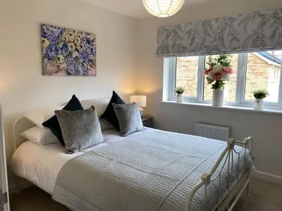 a bedroom with a bed with pillows and a painting at Comfortable new home in Isleham in Ely