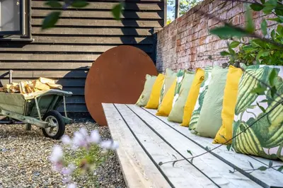 a row of pillows on a bench next to a brick wall at The Firs in Cratfield