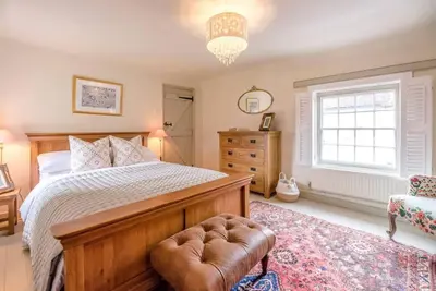 a bedroom with a bed and a chair and a window at Lantern Cottage, Debenham in Stowmarket