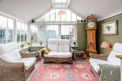 a living room with white chairs and a grandfather clock at Lantern Cottage, Debenham in Stowmarket